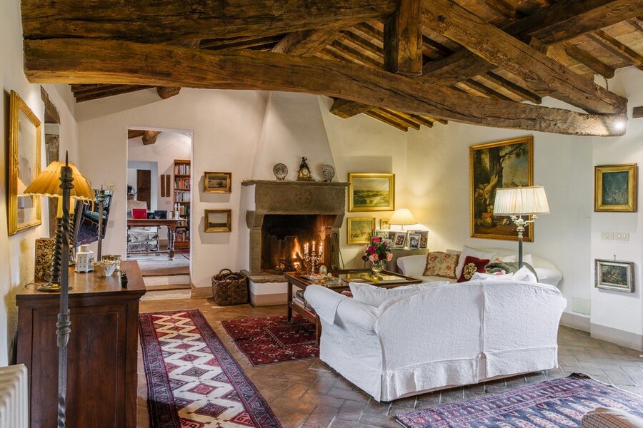 Grosses Wohnzimmer mit Holzbalkendecke und offenem Kamin im Ferienhaus in Italien