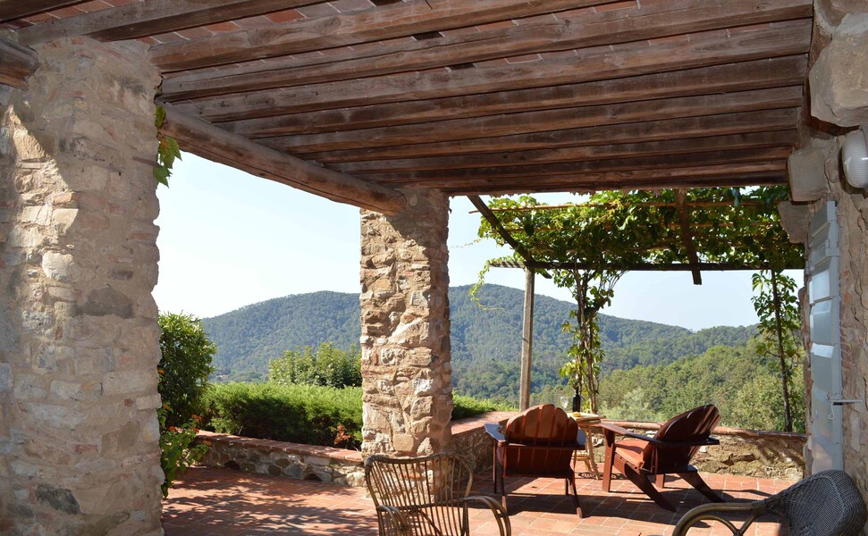 Die überdachte und weitläufige Veranda der Ferienvilla Compignano Barn mit Ausblick auf die grünen Hügel der Umgebung
