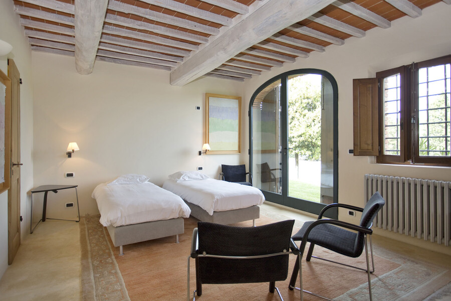 Dieses lichtdurchflutete Schlafzimmer im La Maccinaia bietet direkten Zugang zum Garten der Villa