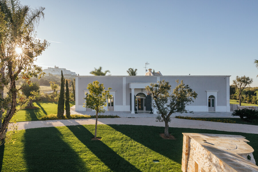 Villa in Apulien mit Palmen im Abendlicht mit Ostuni im Hintergrund