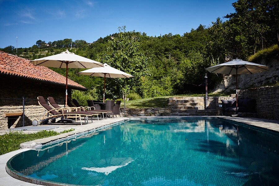 Privater Pool mit Sonnenschirmen und Liegen im Ferienhaus im Piemont