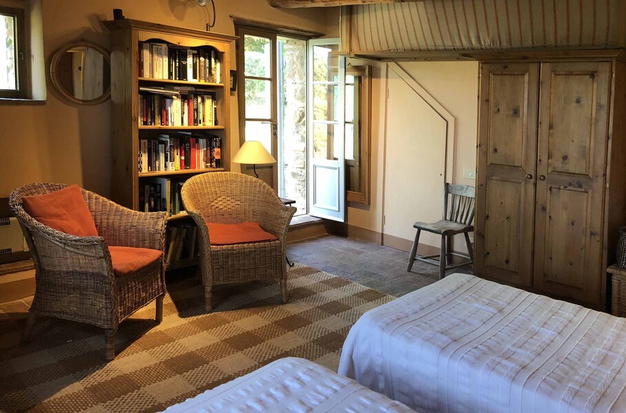 Doppelbettzimmer der Ferienvilla Compignano Barn mit gemütlichen Sesseln und eigenem Zugang nach draußen